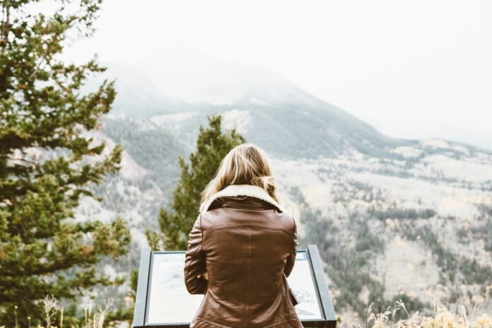 Photo by Thomas Kelley back photo of woman wearing black leather jacket in front of snowed mountain