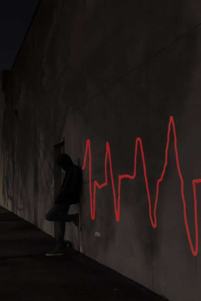 Photo by Ty Tomlinson a man sitting on a skateboard in front of a wall