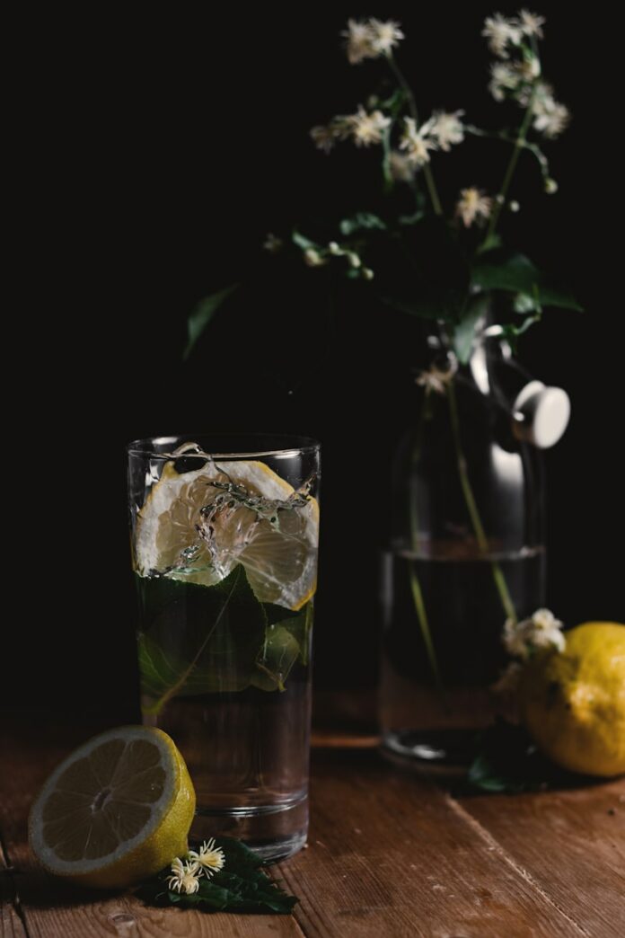 Photo by Henry Be clear drinking glass and sliced lemons on wooden surface