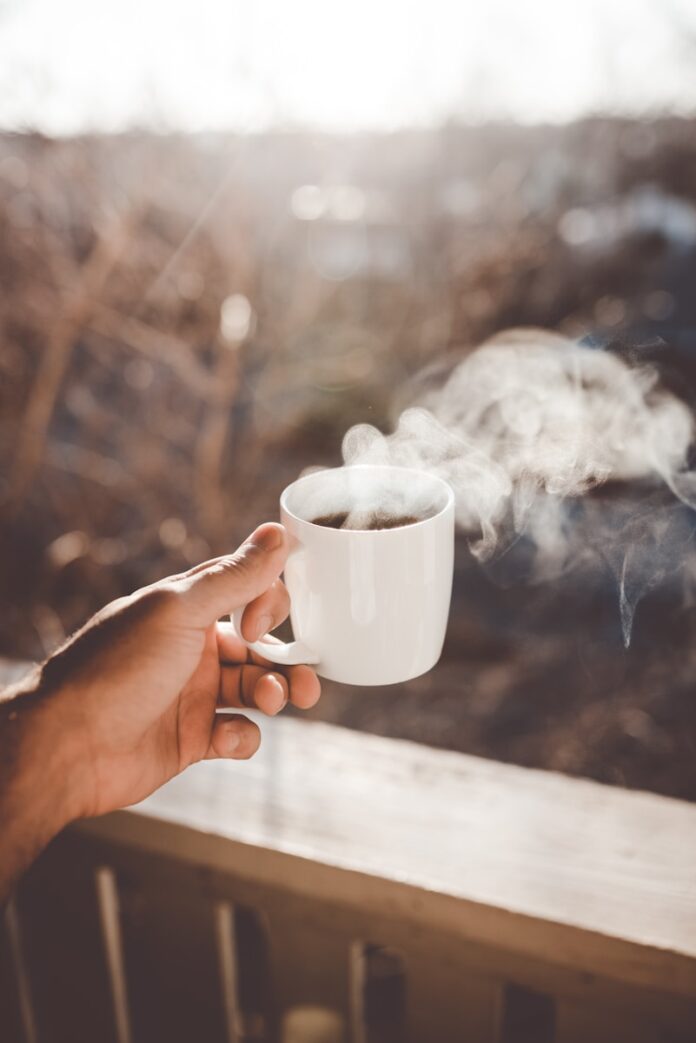 Photo by Clay Banks person holding white ceramic cup with hot coffee