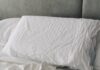 수면의 질 높이는 생활 습관 변화, 실천이 답이다 A rumpled white duvet and pillows on a bed.