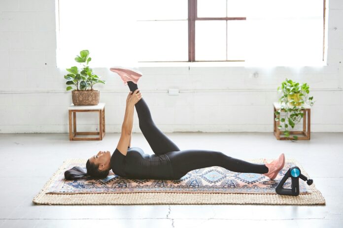 Photo by LittPro Inc woman in black tank top and black leggings lying on black and white floral area rug